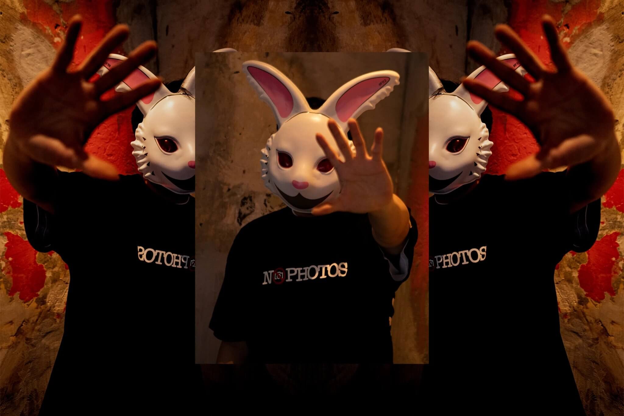 Seorang pria dengan topeng kelinci ala FXXKING RABBITS mengenakan kaos hitam bertuliskan “No Photos”